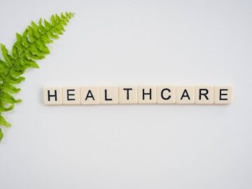 a wooden block spelling the word healthcare next to a green plant